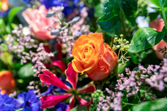 Oranje roos in boeket met kleurige bloemen