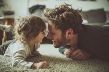 Father and child laughing together in bed,