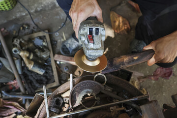 Focused craftsman grinding metal blade in workshop. This manual labor of sharpening steel knife with power tool shows true industrial skill and concentration