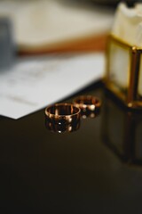 Couple's wedding rings placed on a table with a notebook and decorations nearby during an indoor setting
