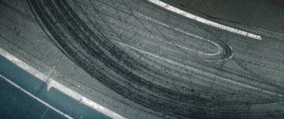 Top-down shot of asphalt road featuring tire skid marks on racetrack surface