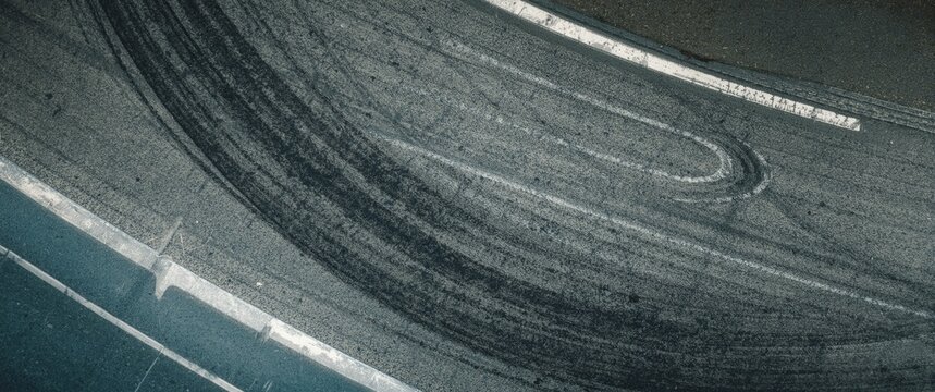 Top-down shot of asphalt road featuring tire skid marks on racetrack surface