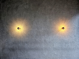 Two Modern Wall Sconces Illuminating a Textured Concrete Wall.