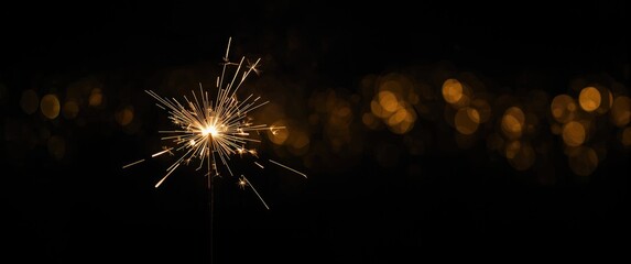 Fototapeta premium Isolated Sparkler Against Black Background with Defocused Lights and Bokeh