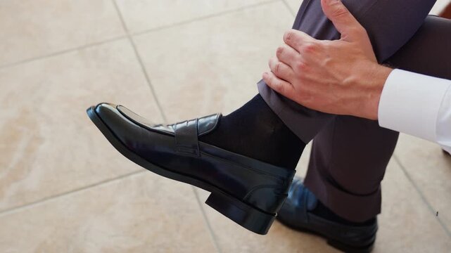 Close-up of groom adjusting dress shoe while getting ready for wedding ceremony.