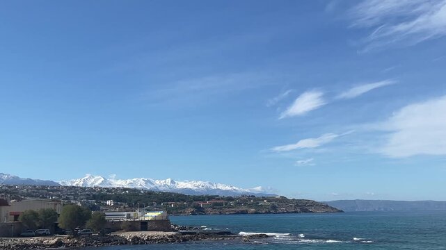 Horizontal panorama: Rethymno city coast view of snow capped White Mountains, Crete sea landscape, Greece travel.