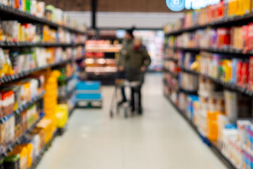 Blurry image of shoppers in grocery store aisle with colorful products