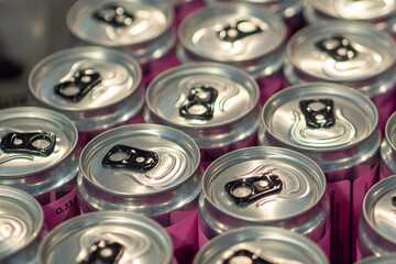 Obraz premium Rows of silver soda cans with pink labels on a purple background