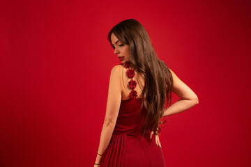 Naklejka premium Woman in red dress stands against a red background, expressing beauty during Valentines Day celebration in a studio setting