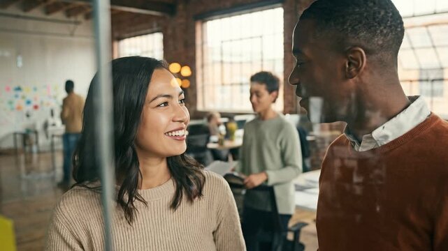 Creative team work together on project in modern office. Diverse professionals collaborate, smile, plan, and share ideas using sticky notes on glass wall. Team members strategize in a collaborative wo