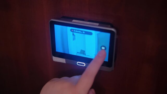 Woman hand recording front door peephole security camera. Technology and home secure system concept. 