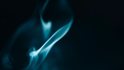 Fototapeta premium Abstract blue smoke swirls on a black background, mystical ethereal flame effect