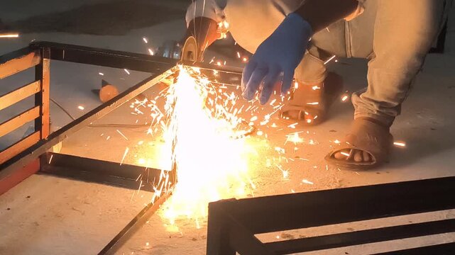 Metal grinding process captured with bright sparks flying from an angle grinder during industrial cutting work. This powerful scene highlights fabrication skills, workshop energy,