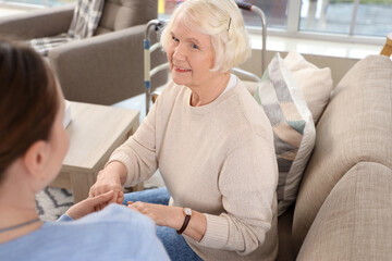 Obraz premium Caregiver and senior woman sitting on sofa in nursing home