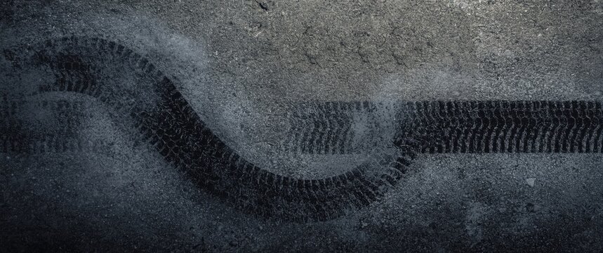 Top-down aerial perspective showing abstract texture and background with car tire drifts and skid marks on a road race track, black tire marks on street racing circuit, automotive theme