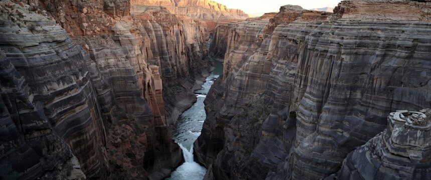 Flood waters forming smooth vertical chutes in canyon walls against a rocky landscape backdrop