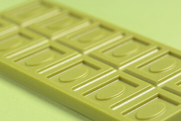 Sweet matcha chocolate bar on green background, closeup