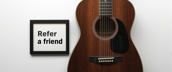Fototapeta premium Guitar and photo frame displaying 'Refer a friend' text, white background, concept of referral marketing