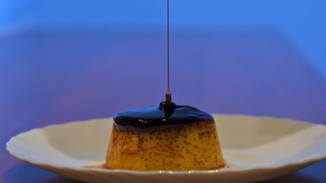 Pouring dark berry syrup over an egg flan