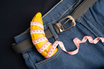 Banana with measuring tape on jean trousers, penis health.