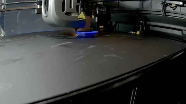 Timelapse of 3D printer extruding blue plastic bird ocarina whistle on build plate, showing FDM additive manufacturing process, DIY maker prototyping and fabrication