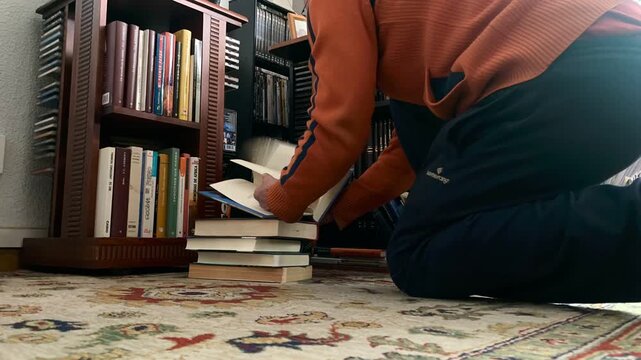 Bibli&oacute;filo hojeando libros de rodillas y pasando p&aacute;gina de obras literarias time lapse y ordenando lectura en estanter&iacute;a