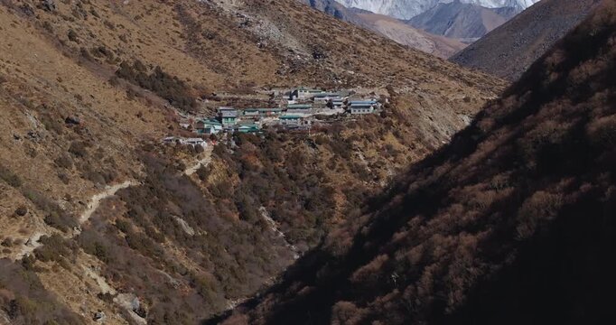 Slow forward-moving aerial shot panning up from Shomare village to reveal Mount Everest and Ama Dablam. High-altitude residential settlement located along the Everest Base Camp trek in Nepal.
