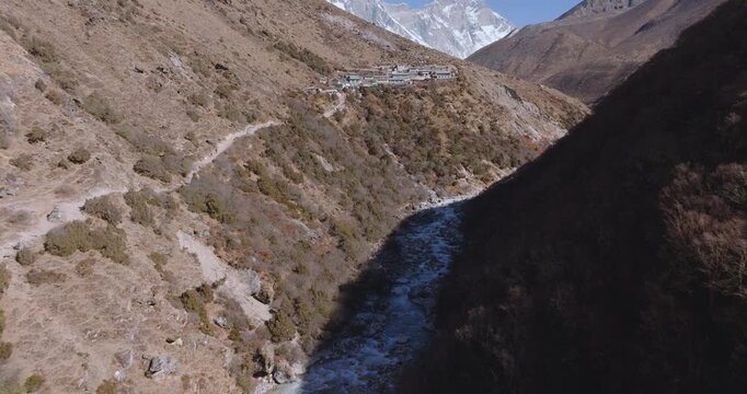 Upward tilting aerial drone shot revealing the Dudh Koshi River, Shomare village, and surrounding Himalayan mountains along the Everest Base Camp trek route in Nepal.