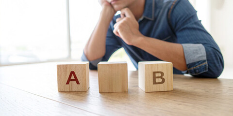 Concept of decision making in business and blocks labeled A and B placed on a table behind a businessman represents analytical thinking.