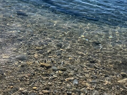 Crystal clear sea shallow water with pebbles stones at the bottom.