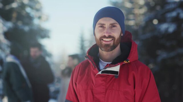Smiling man in winter gear, Warmly smiling man in layered clothing exploring sunlit pine woodland with friends