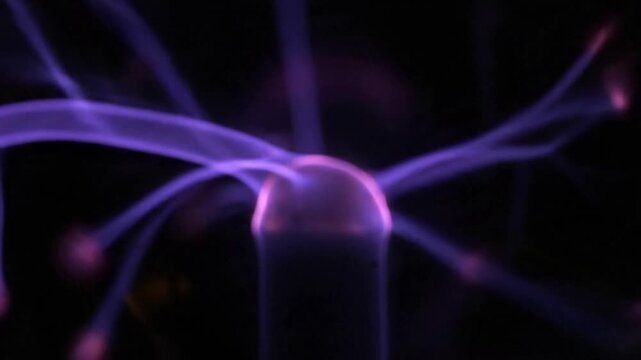 Electricity discharge in a plasma globe with purple light.