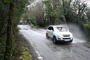 White SUV splashing through a flooded road in West Sussex during the floods of january 2026. 