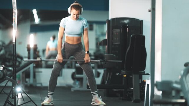 Athletic woman performing sumo deadlift in gym
