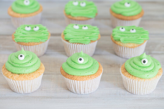 Close-up of homemade cupcakes with buttercream frosting decorated with googly eyes to look like monsters