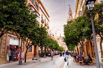 Fototapeta premium People walking along one of main streets in center beautiful city Seville, with old architecture and restaurants, Spain. Life on streets Andalusia.