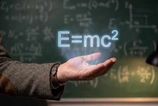 Scientist hand holding glowing relativity energy equation above palm near green math chalkboard