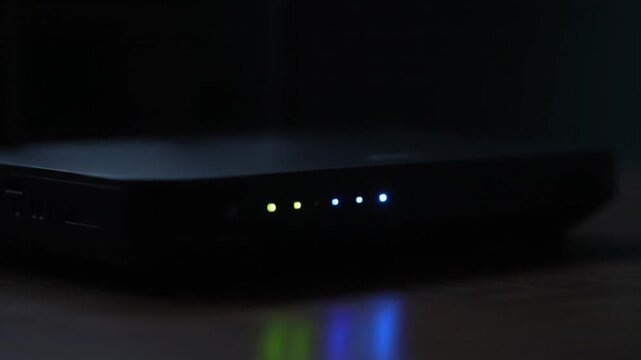 Close-up of a dark electronic device with four illuminated indicator lights on a dark background with a shallow depth of field.