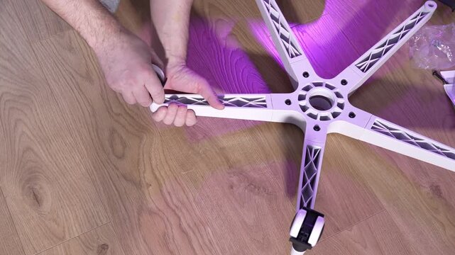 Installing caster wheels into plastic base of office chair during assembly