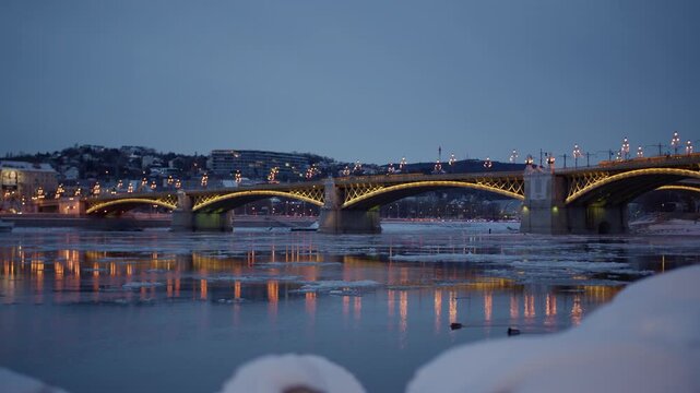 Margaret Bridge Spanning The Partially Frozen Danube River At Night In Budapest, Hungary. - wide shot