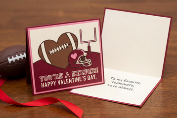 Handmade American football themed Valentine's Day greeting card with funny text You're a Keeper and red ribbon on a wooden table for a sports fan