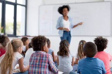 Fototapeta premium African American teacher pointing at whiteboard to diverse children sitting on classroom floor