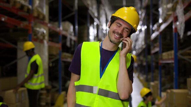 Warehouse professional wearing protective safety gear communicating via mobile phone, displaying varied facial expressions while colleagues work amid storage shelves and logistics environment