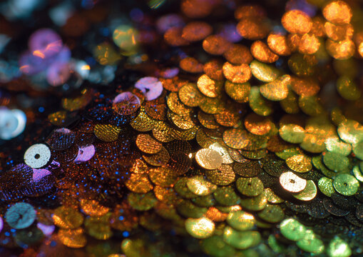 Close-up of sparkling sequins texture with glittering reflective surface, vibrant colors, and glamorous macro detail.
