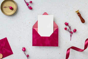 Romantic magenta envelope with a blank invitation card on a textured grey background.