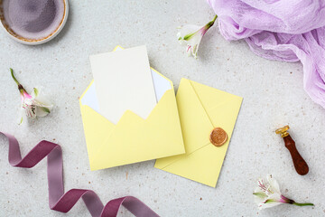 Yellow wedding stationery mockup with purple ribbon and lilac fabric on stone background.