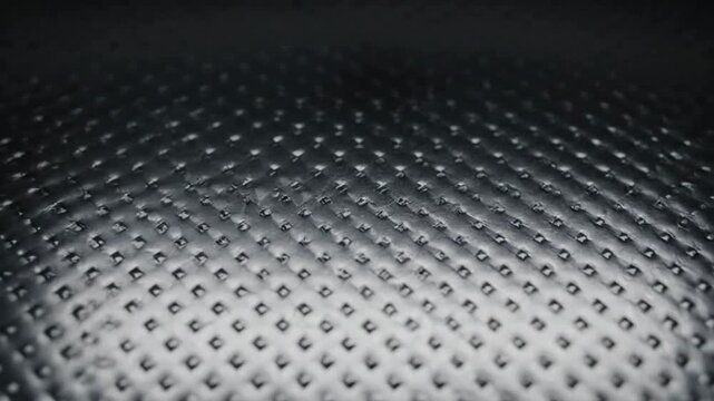 Metal grid surface with perforated pattern and reflective finish.