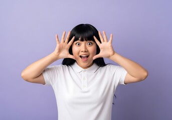 Surprised young woman with hands up against a purple background