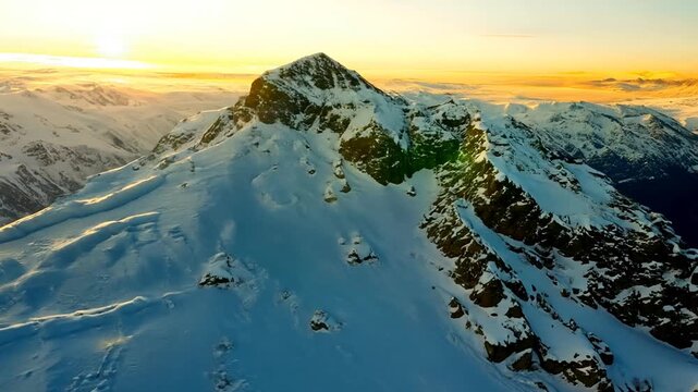 A slow 8-second aerial flight over a vast, snow-covered mountain range during golden hour. The camera approaches a central rugged peak, highlighting the vibrant sunrise/sunset light reflecting off th