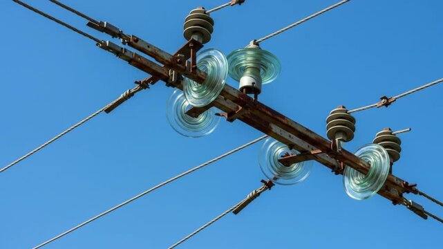 Power line insulators holding cables against blue sky